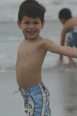 boy in his blue swim shorts at the beach
